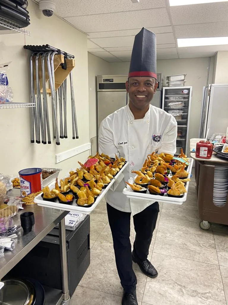 Chef Joel carrying trays of Cuban dishes