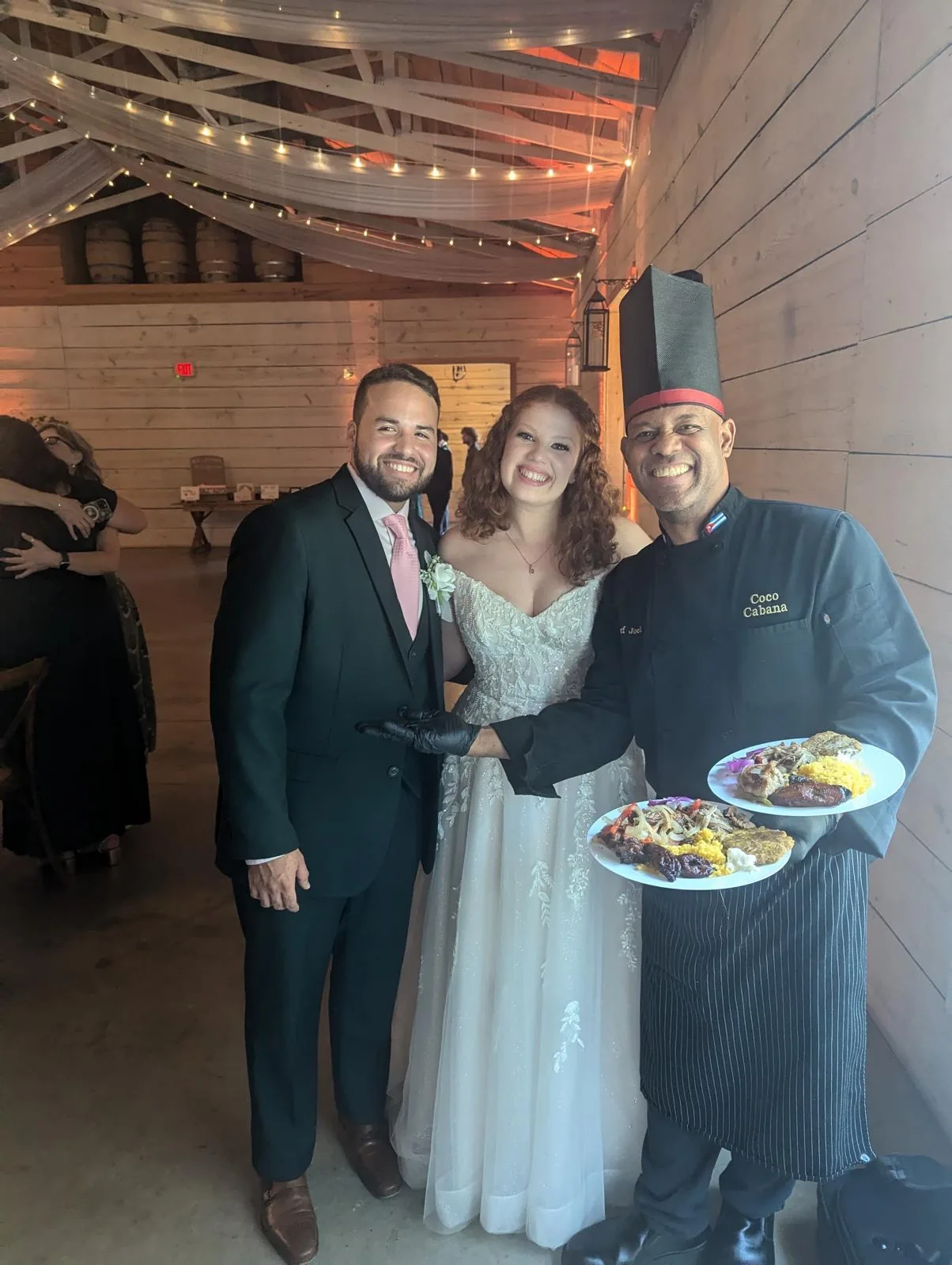 Chef Joel presenting plated dinners to a barn-venue couple