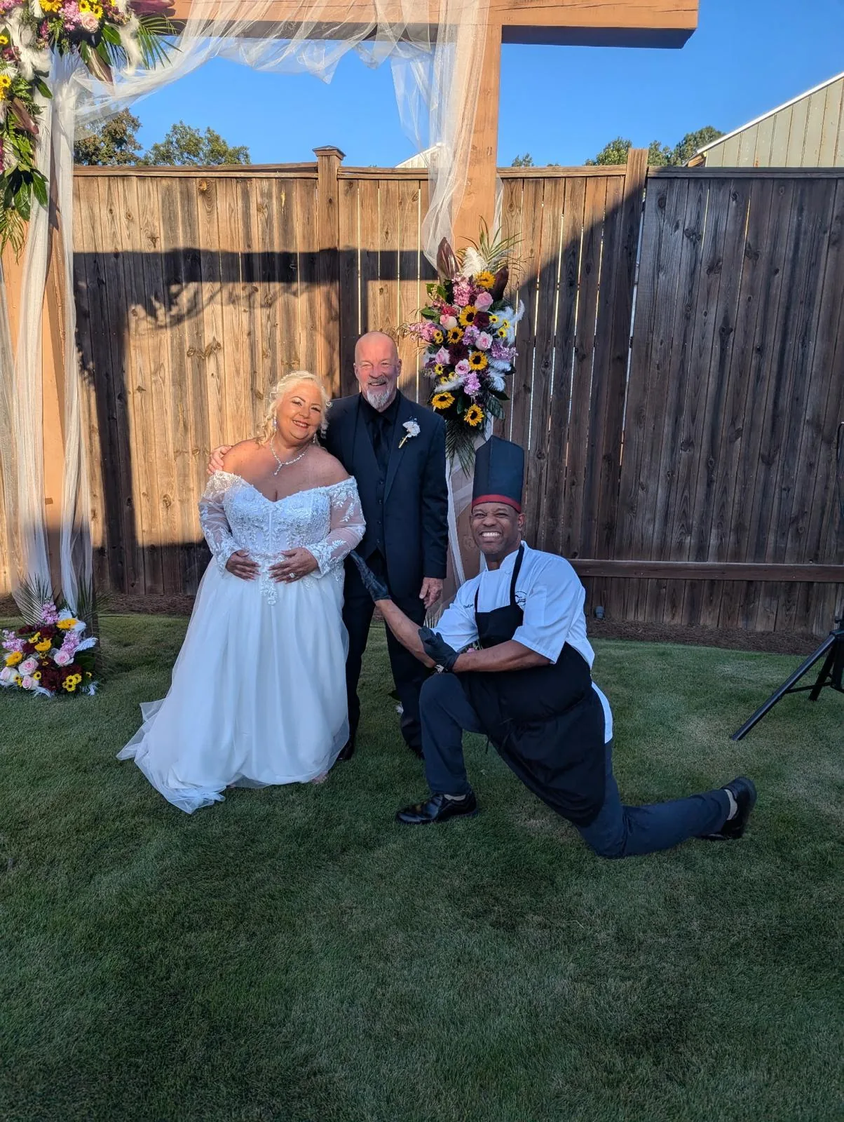 Chef Joel with a couple under their outdoor wedding arch
