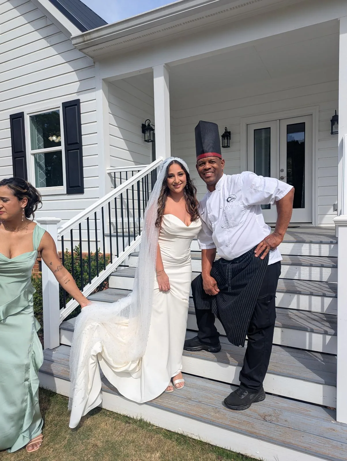 A bride and groom with Chef Joel on the venue porch